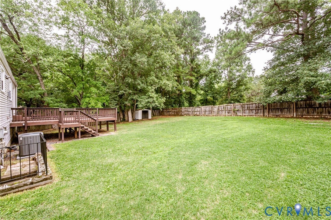 9406 Emmett Court, Glen Allen, VA 23060 Expansive backyard featuring a manicured lawn, mature tree canopy, and wooden deck with multiple levels