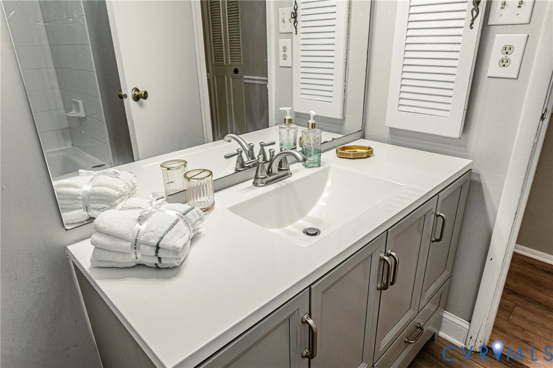9406 Emmett Court, Glen Allen, VA 23060 Spa-inspired primary bathroom vanity featuring a spacious white quartz countertop, dual-sink configuration with chrome fixtures, soft-close cabinetry in a neutral gray finish, and abundant storage