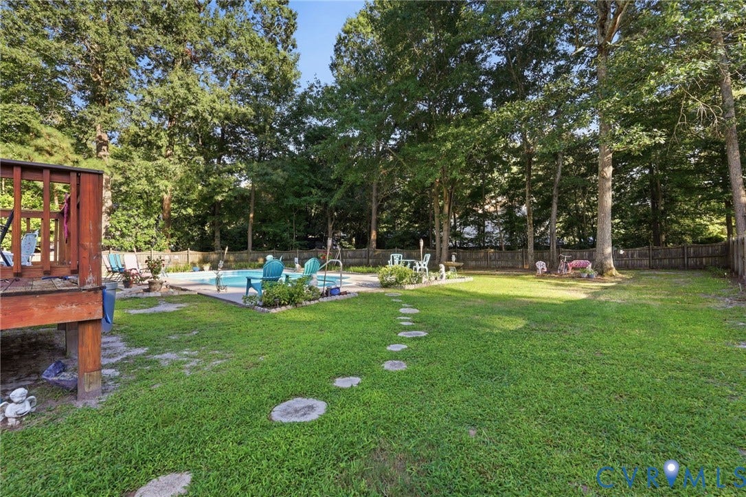3819 Glen Oaks Court, Chester, VA 23831 Expansive backyard featuring a rectangular swimming pool with surrounding concrete patio, a multi-level wood deck, a stone paver pathway, and mature trees providing natural screening
