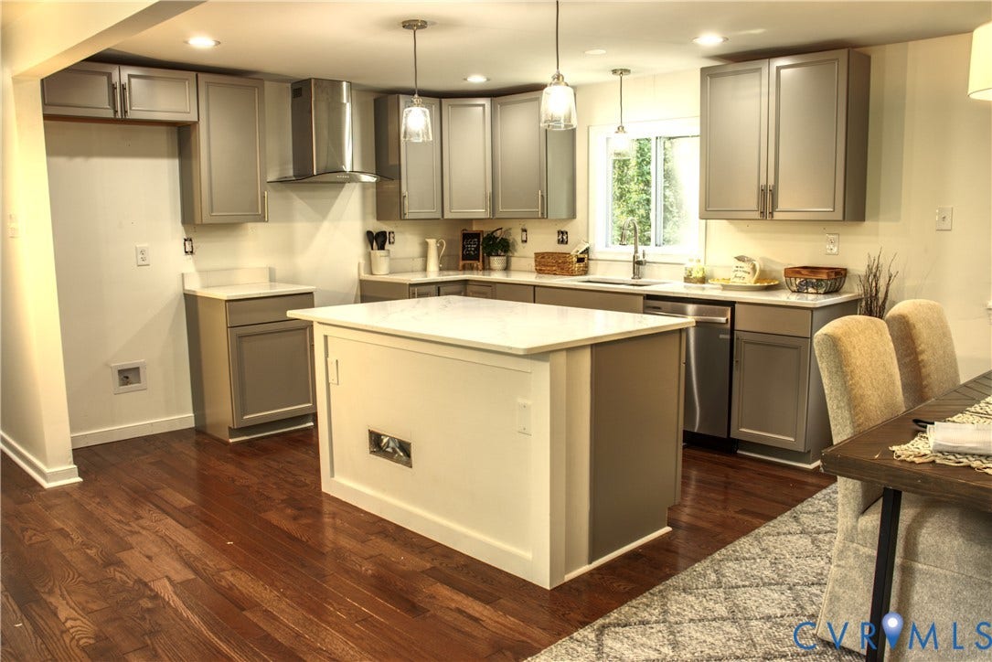 5004 Fairlake Lane, Henrico, VA 23060 Renovated kitchen featuring a central island with white paneling and a light countertop, gray shaker-style cabinetry, stainless steel appliances, recessed lighting, and wood-finish flooring
