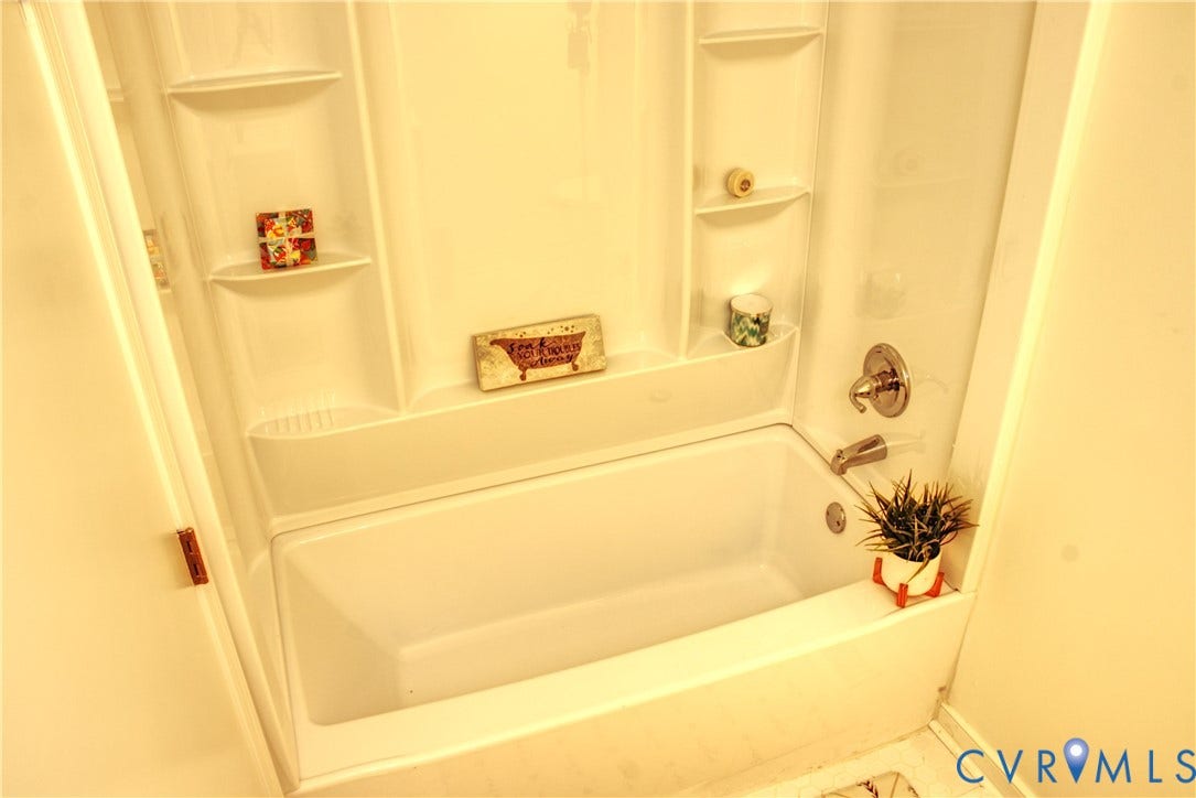 5004 Fairlake Lane, Henrico, VA 23060 White bathtub and shower combination unit featuring integrated shelving
