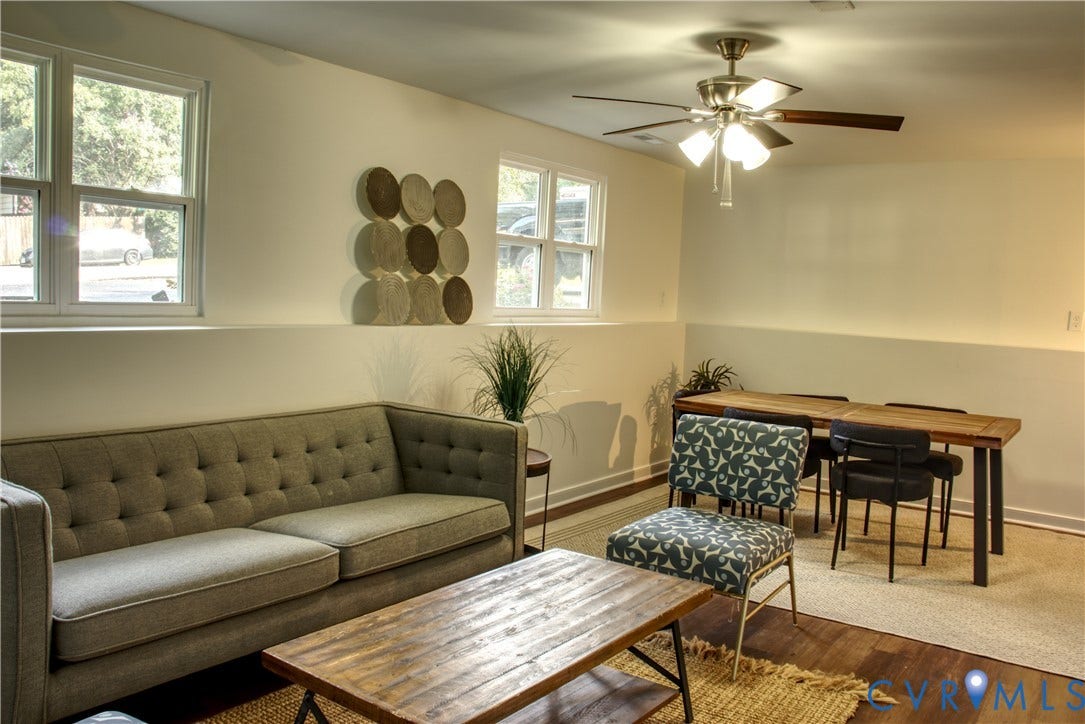 5004 Fairlake Lane, Henrico, VA 23060 Bright living area featuring wood-finish flooring, multiple windows, a ceiling fan with integrated lighting, and a two-tone wall treatment