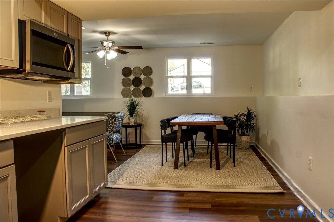 5004 Fairlake Lane, Henrico, VA 23060 Open-concept kitchen and dining area featuring wood-finish flooring, two large windows, a ceiling fan, and modern cabinetry with a built-in microwave