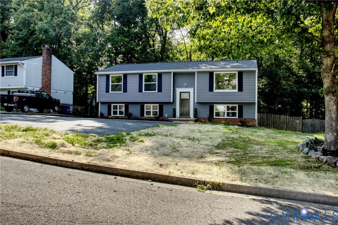 5004 Fairlake Lane, Henrico, VA 23060 Split-level home featuring grey siding, dark blue shutters, a dark wood-finish front door with a transom window, and white window frames