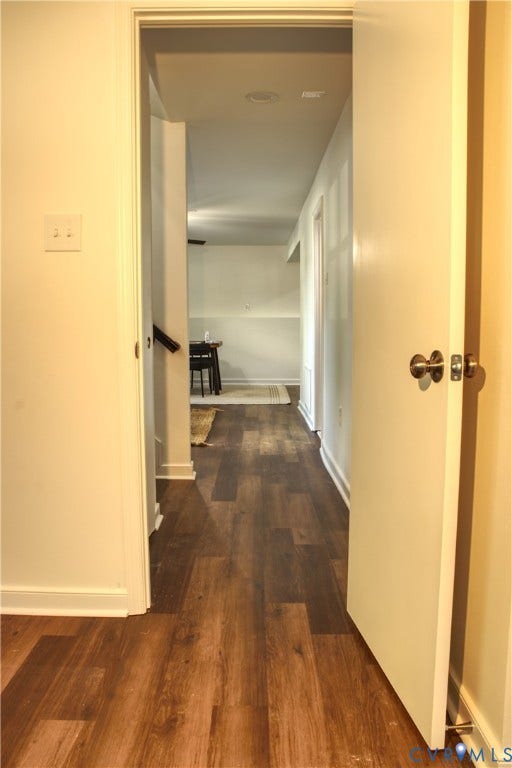 5004 Fairlake Lane, Henrico, VA 23060 Hallway with wood-finish flooring, white baseboards, and a solid core door with brushed brass hardware