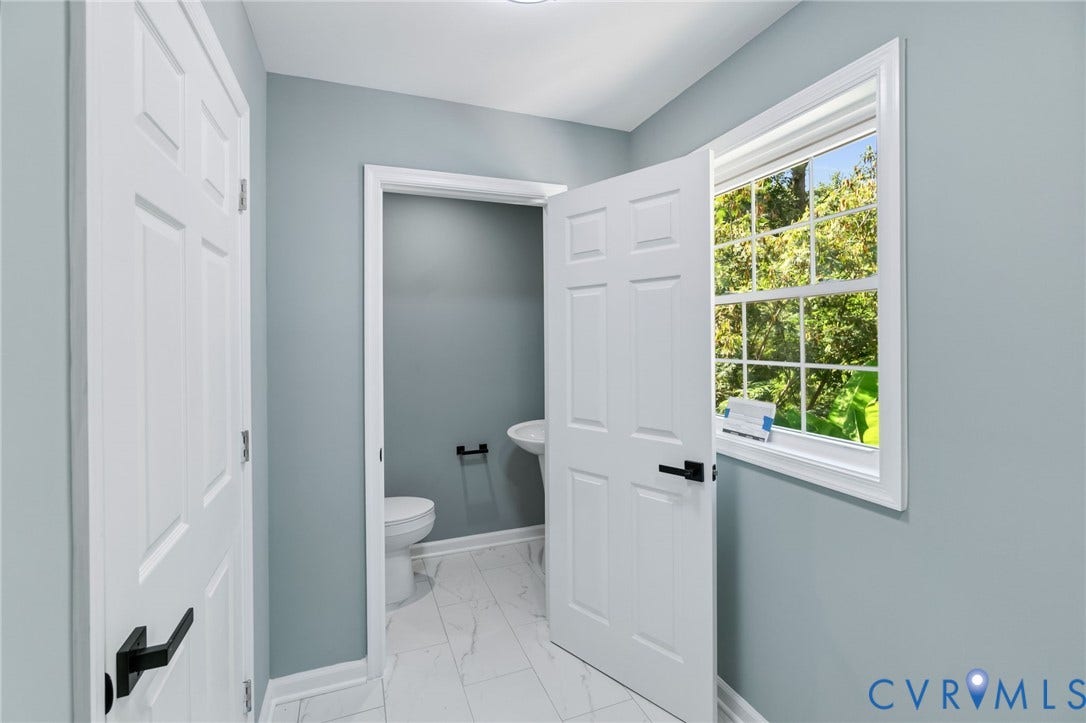 White paneled doors with matte black hardware, a large multi-pane window, and light-toned flooring