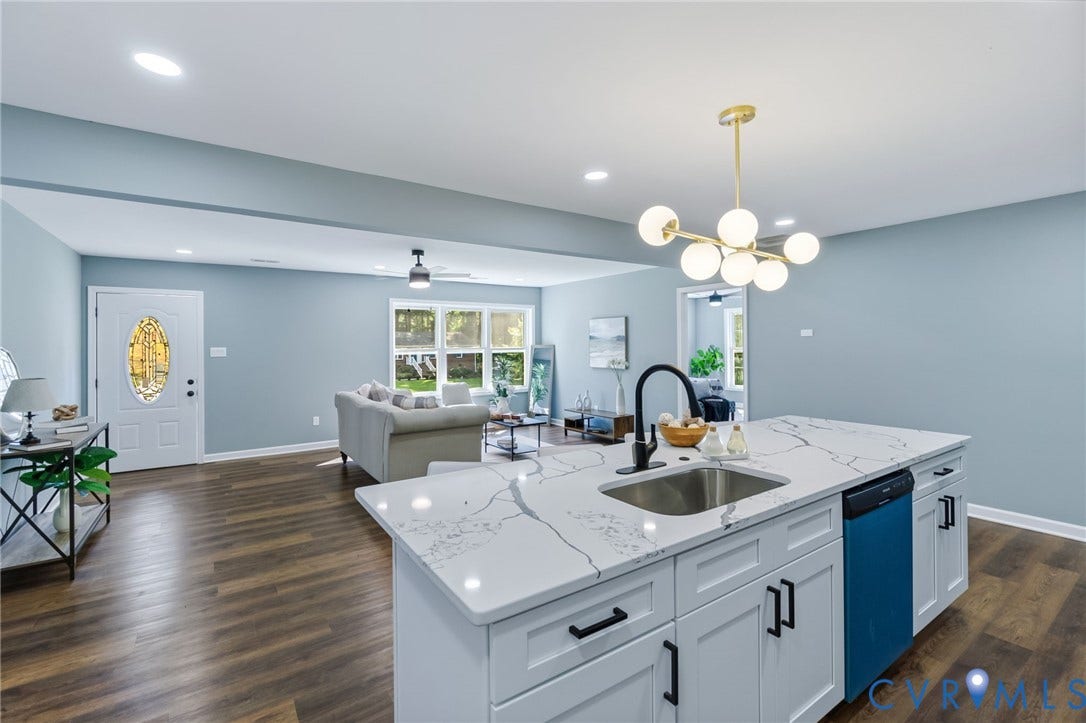 Kitchen island with white cabinetry, a black faucet, and a stainless steel sink