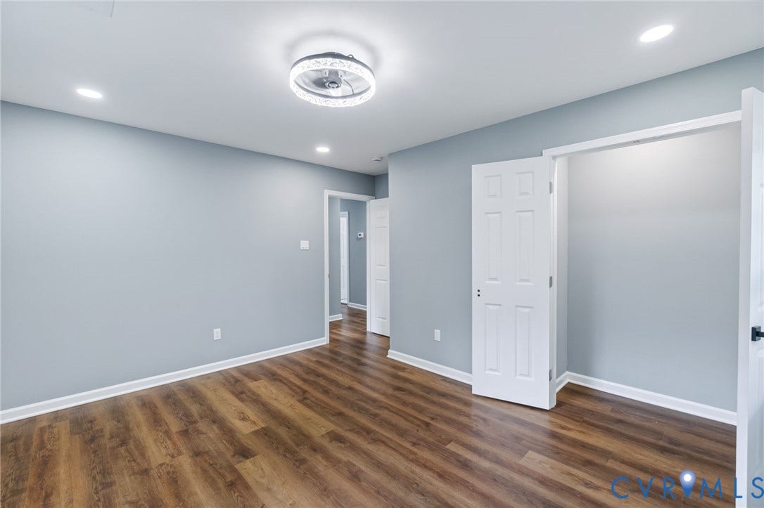Wood-finish flooring with white trim, recessed lighting, and a decorative semi-flush ceiling fixture