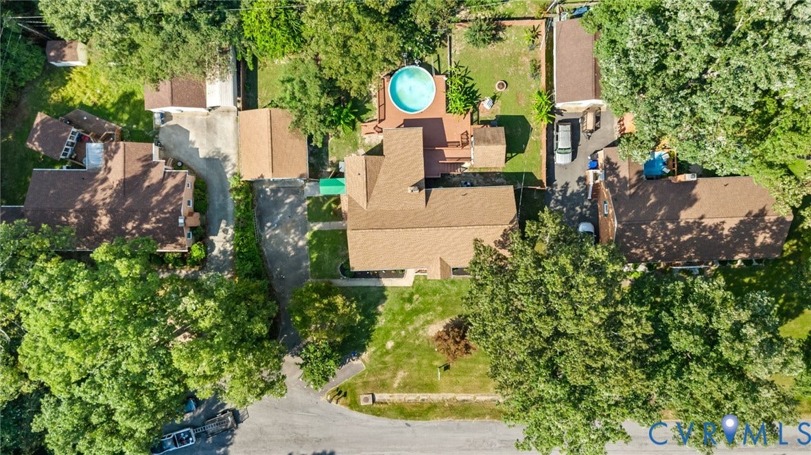Expansive lot featuring a primary residence with a brown shingle roof, a detached garage, a secondary outbuilding, a circular above-ground pool, and a dedicated driveway