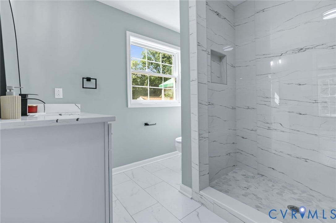 Walk-in shower with full-height tile surround, built-in shower niche, and glass enclosure