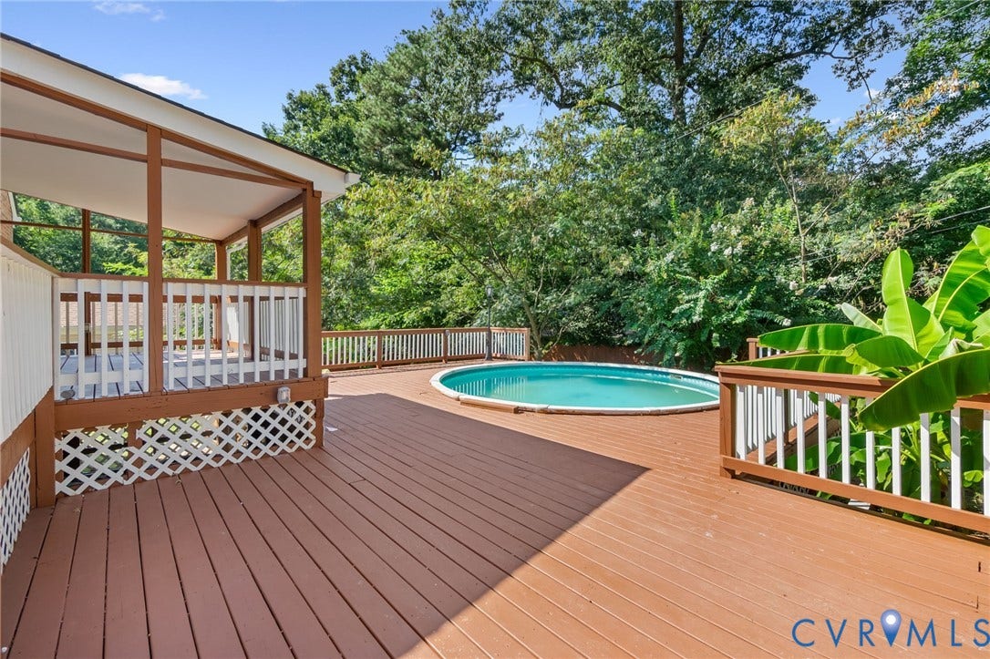 Expansive wood-finish deck with an integrated above-ground pool, covered patio, and white lattice detailing