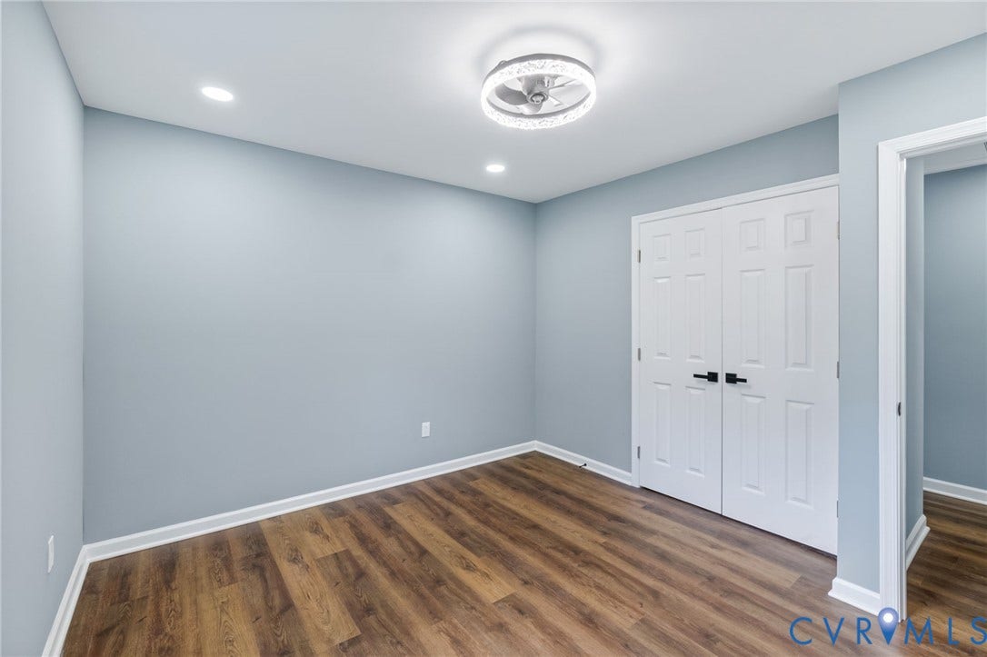 Wood-finish flooring with white trim, recessed lighting, and a decorative semi-flush mount ceiling fixture