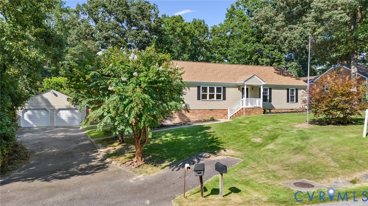Ranch-style residence featuring a prominent front porch, a two-car garage with an asphalt driveway, and a sloped front lawn