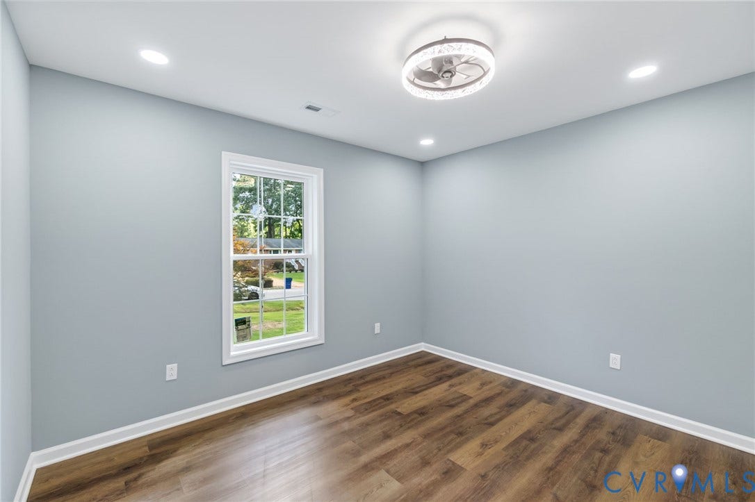 Wood-finish flooring with white trim, a double-hung window, recessed lighting, and a flush-mount ceiling fan