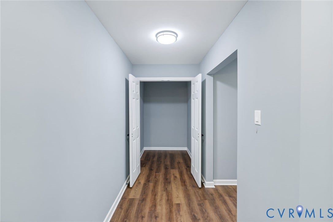 Hallway featuring wood-finish flooring, white trim, and a flush-mount ceiling light