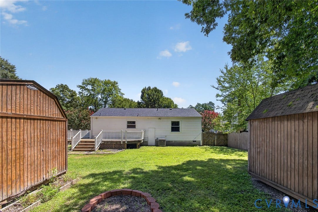 6302 Phobus Court, Richmond, VA 23234 Expansive backyard featuring a light-colored exterior, a multi-level deck with white railings, and two wooden storage sheds
