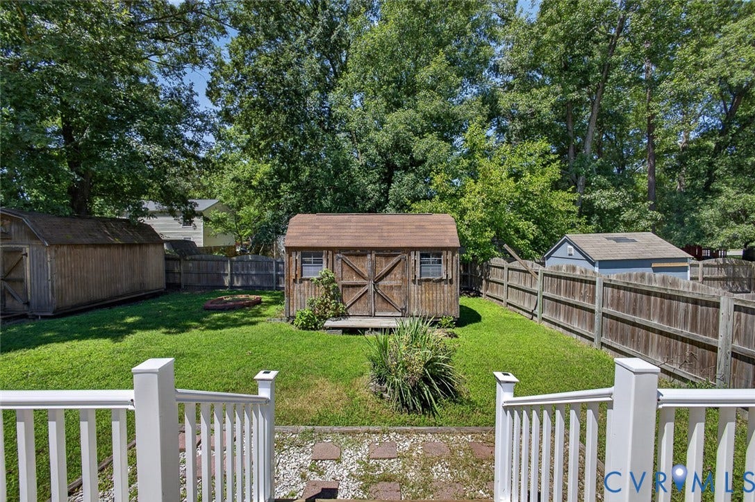 6302 Phobus Court, Richmond, VA 23234 Expansive backyard featuring a central storage shed with double barn doors, a secondary long storage shed, and a third shed with a shingled roof