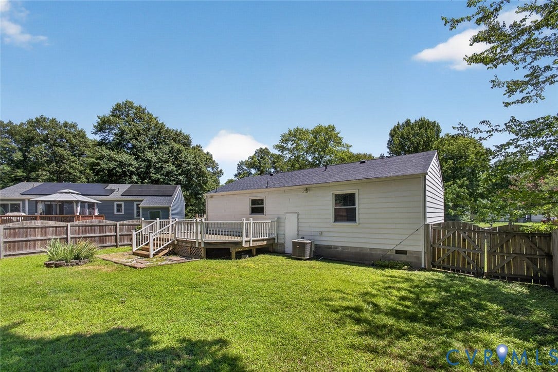 6302 Phobus Court, Richmond, VA 23234 Expansive backyard featuring a wood deck with stairs, a fenced perimeter, and a partial view of the property's exterior siding