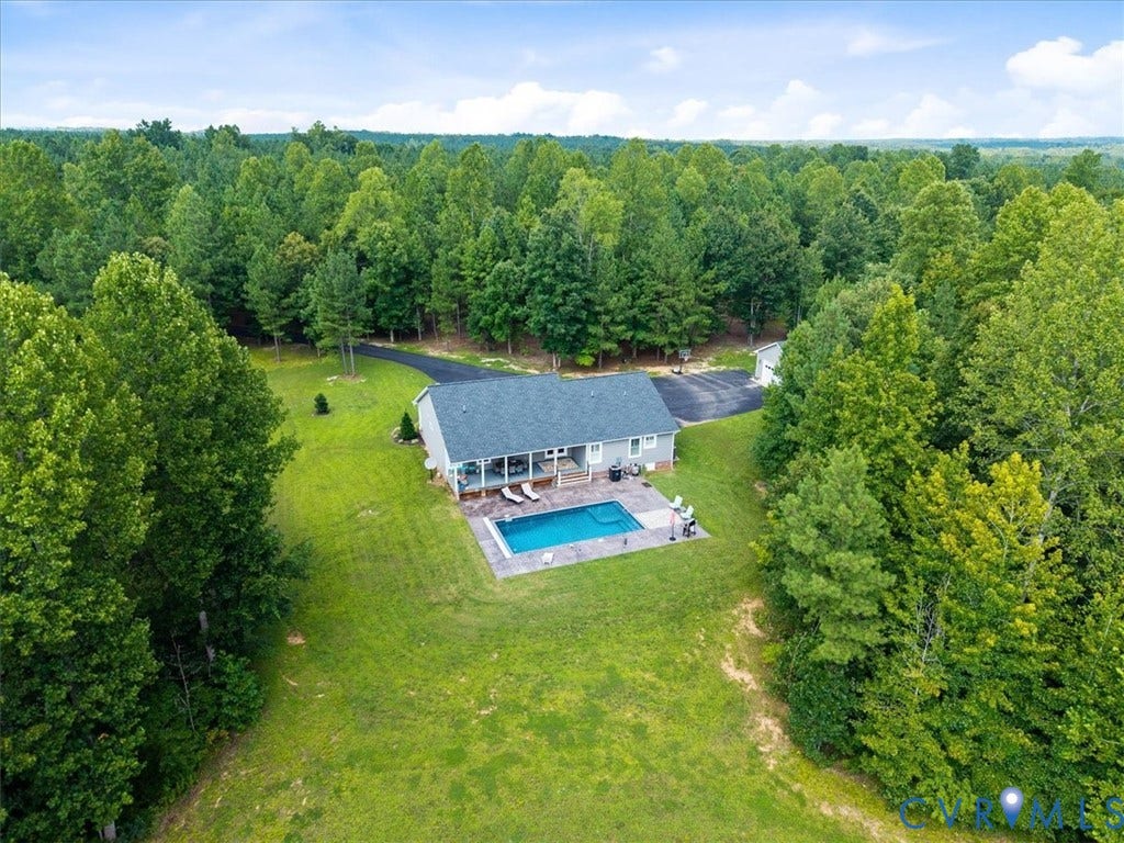 Ranch-style residence featuring a private swimming pool with a surrounding paved deck, a screened porch, and a paved driveway