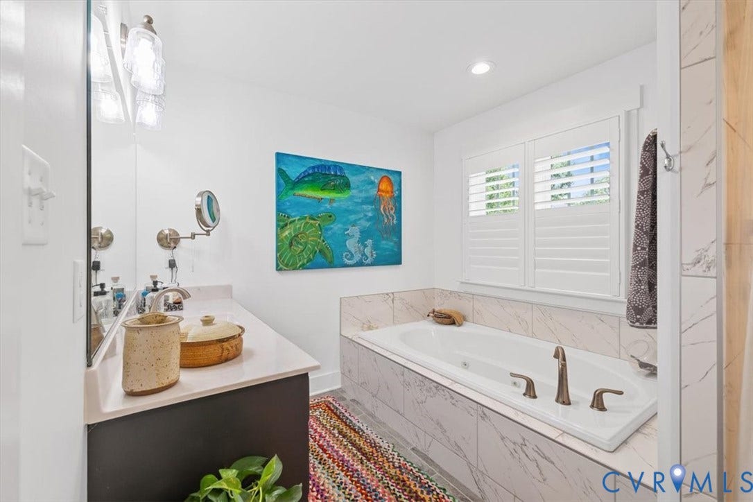White bathroom featuring a built-in tub with bronze fixtures, surrounded by white marble-look tile