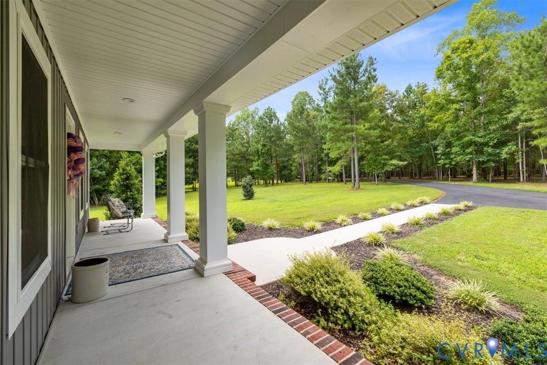 Covered concrete front porch with white support columns, recessed lighting, and a tongue-and-groove ceiling