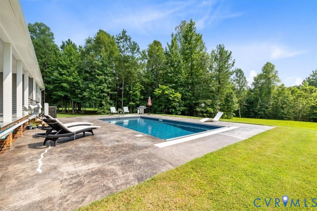 Rectangular in-ground swimming pool surrounded by a textured concrete patio