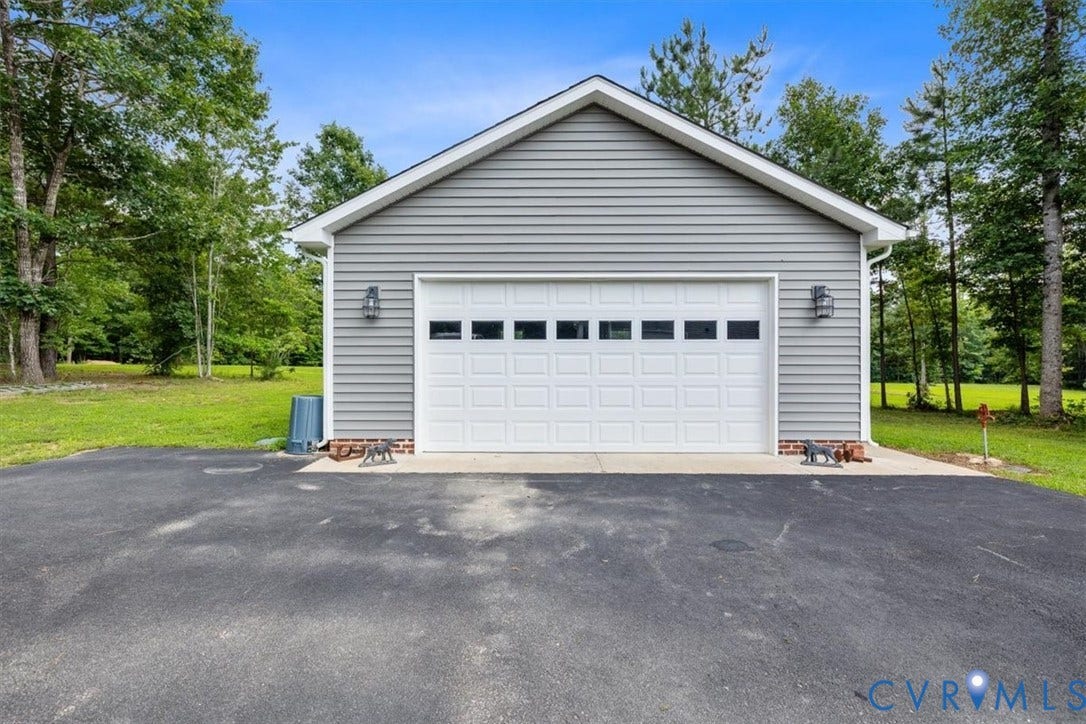 Detached garage featuring horizontal siding, a white panel garage door with windows, and two exterior wall sconces