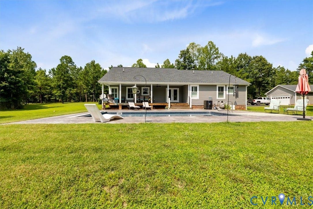 Rear exterior featuring a covered porch, an in-ground swimming pool, a spacious patio, and a detached two-car garage