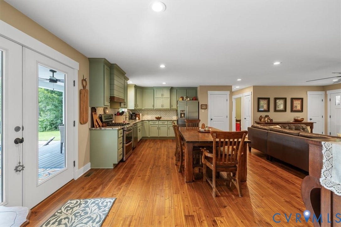 Open-concept interior featuring wood-finish flooring, recessed lighting, and a kitchen with mint green cabinetry and stainless steel appliances