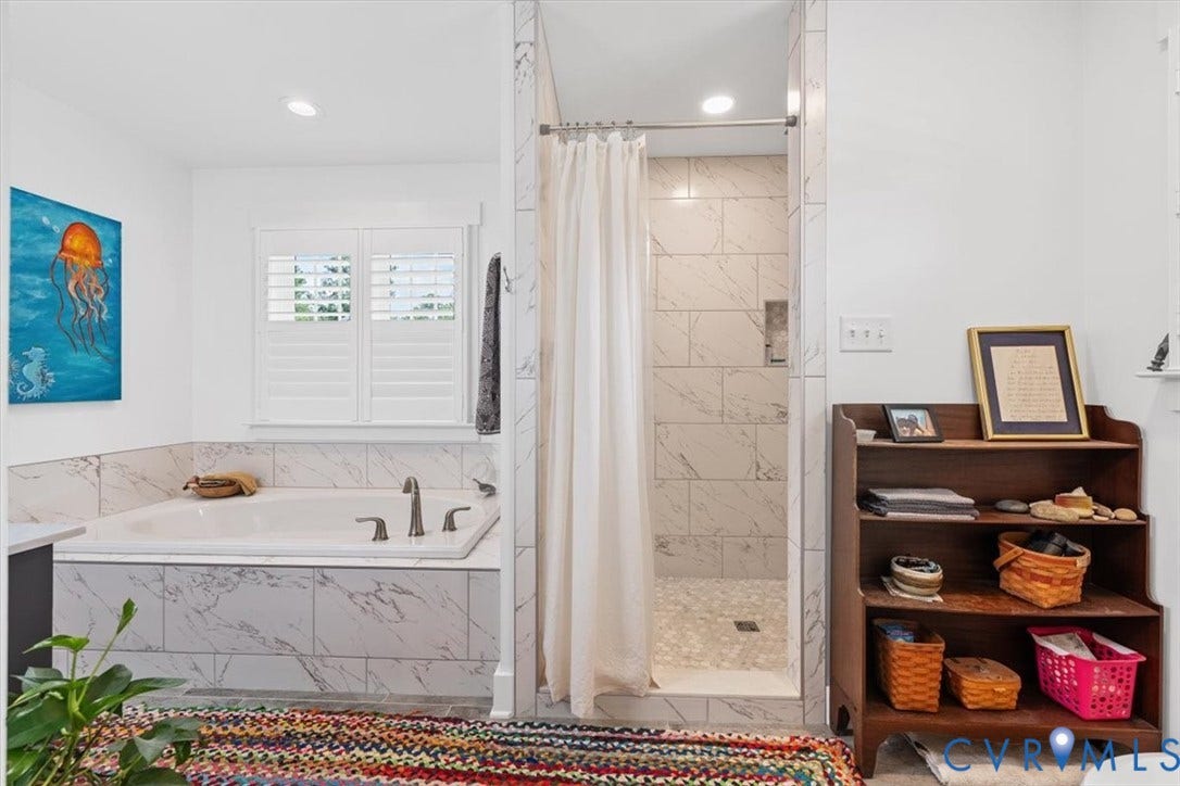 Built-in soaking tub with marble-look tile surround and plantation shutters