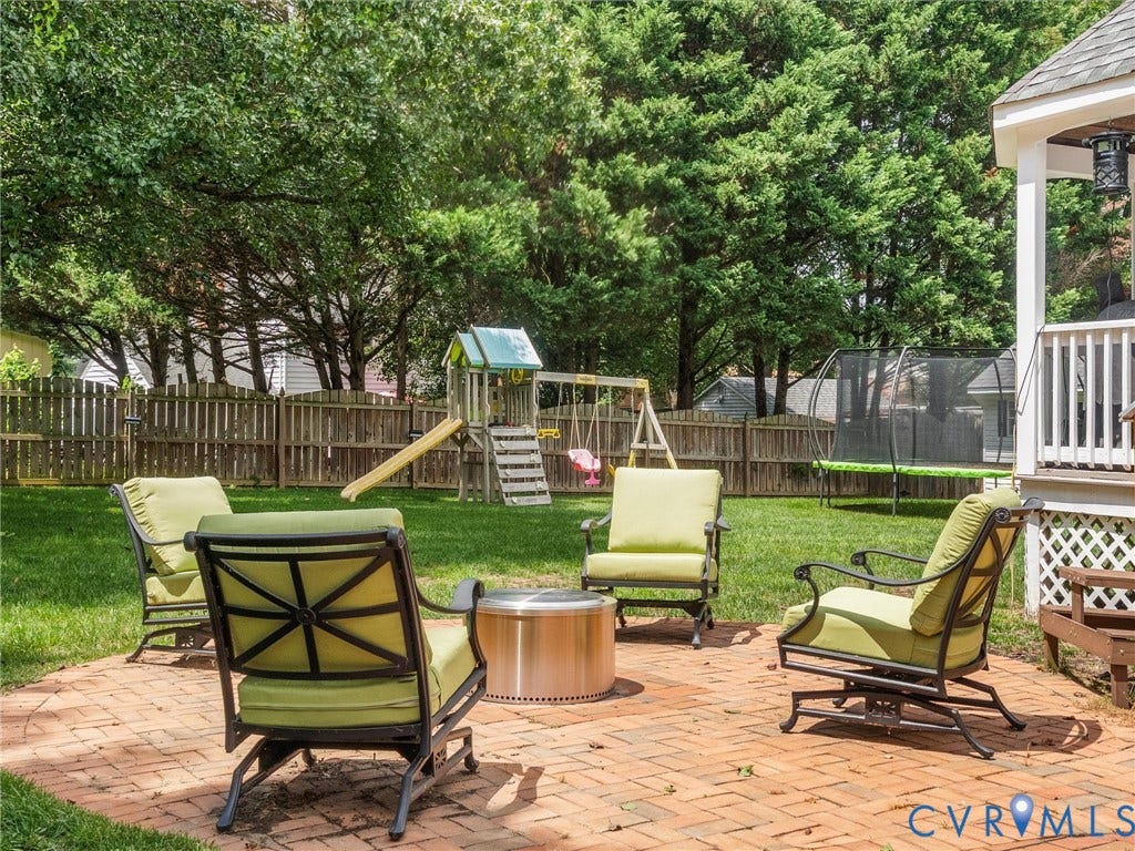 8216 Indian Springs Road, Richmond, VA 23237 Expansive backyard featuring a brick paver patio, a manicured lawn, a wood privacy fence, and mature trees providing natural screening