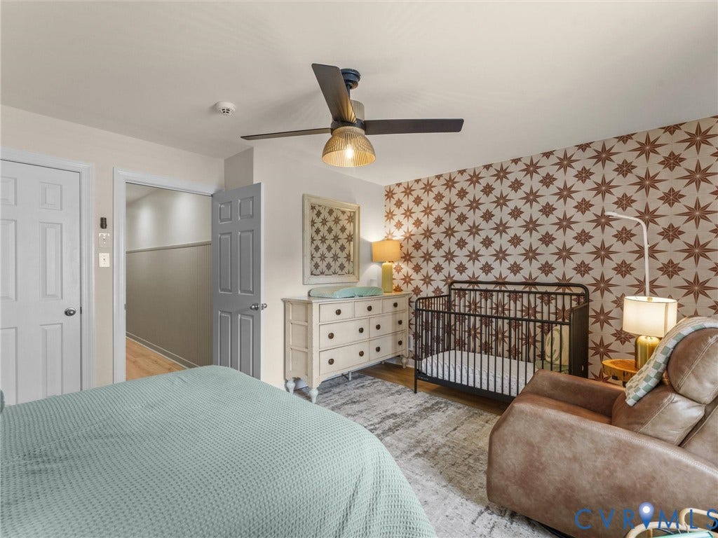 8216 Indian Springs Road, Richmond, VA 23237 Master bedroom suite featuring a ceiling fan with integrated lighting, soft blue bedding on a platform bed frame, and direct access to an ensuite bathroom with half-wall partition