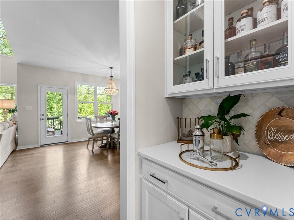 3647 Walkers Creek, Powhatan, VA 23139 Built-in cabinetry with glass-front uppers and a solid countertop, herringbone tile backsplash, wood-finish flooring, and a chandelier