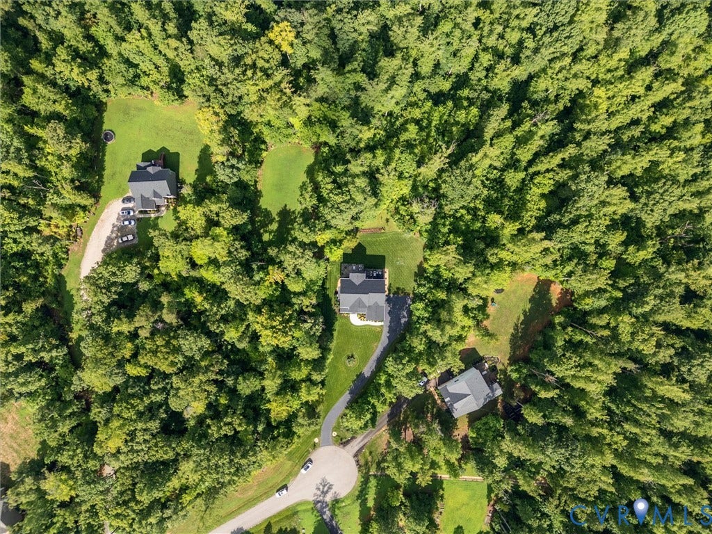 3647 Walkers Creek, Powhatan, VA 23139 Aerial perspective of a property featuring a gray-roofed residence, extensive surrounding mature trees, a paved driveway, and manicured lawn areas