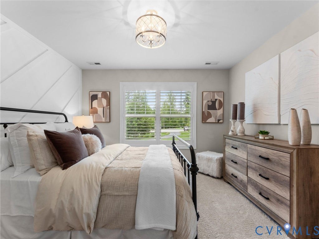 3647 Walkers Creek, Powhatan, VA 23139 Wall with geometric paneling, decorative ceiling light fixture, window with plantation shutters, wood-finish dresser with dark hardware, and light-toned carpeting