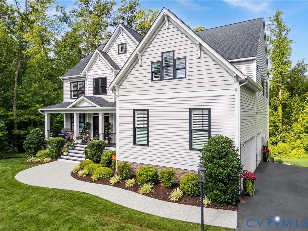 3647 Walkers Creek, Powhatan, VA 23139 Light-colored siding exterior with black-framed windows, a covered front porch, an attached garage, a paved driveway, and established landscaping