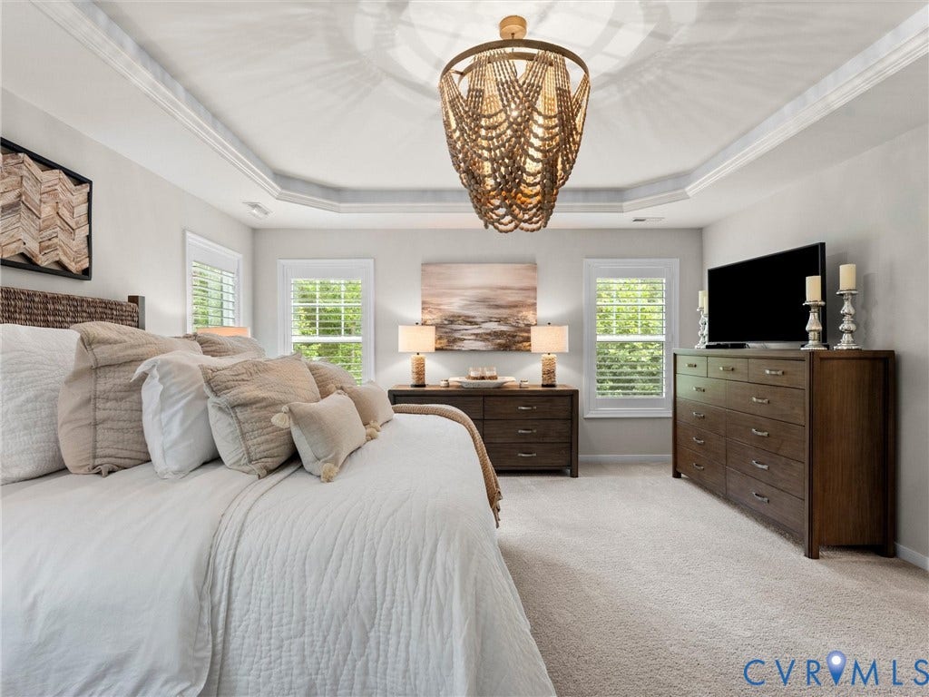 3647 Walkers Creek, Powhatan, VA 23139 Tray ceiling with crown molding, decorative chandelier, two windows with plantation shutters, and light-colored carpeting
