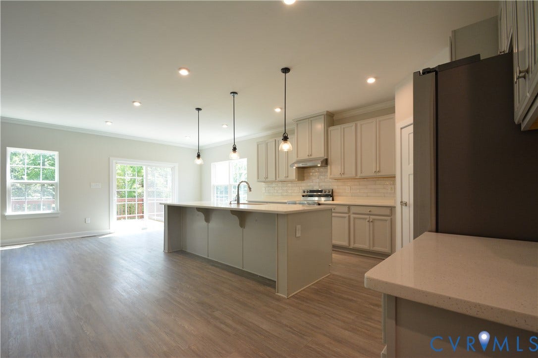 9201 Brett Drive, Bayhill Pointe West, Chesterfield, VA 23112 Spacious kitchen featuring an expansive central island with pendant lighting, light gray cabinetry, white subway tile backsplash, stainless steel appliances, and quartz countertops