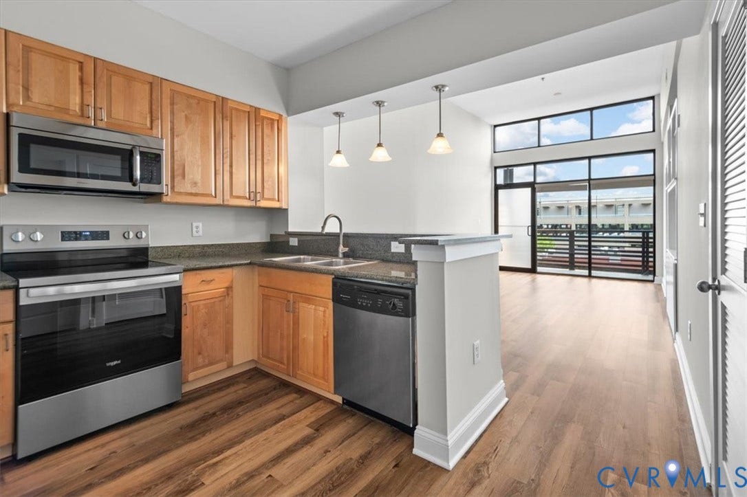1333 Broad Street, #510, Ironhouse Place Condominiums, Richmond, VA 23220 Open-concept kitchen featuring wood-finish cabinetry, stainless steel appliances, and a granite countertop breakfast bar with pendant lighting