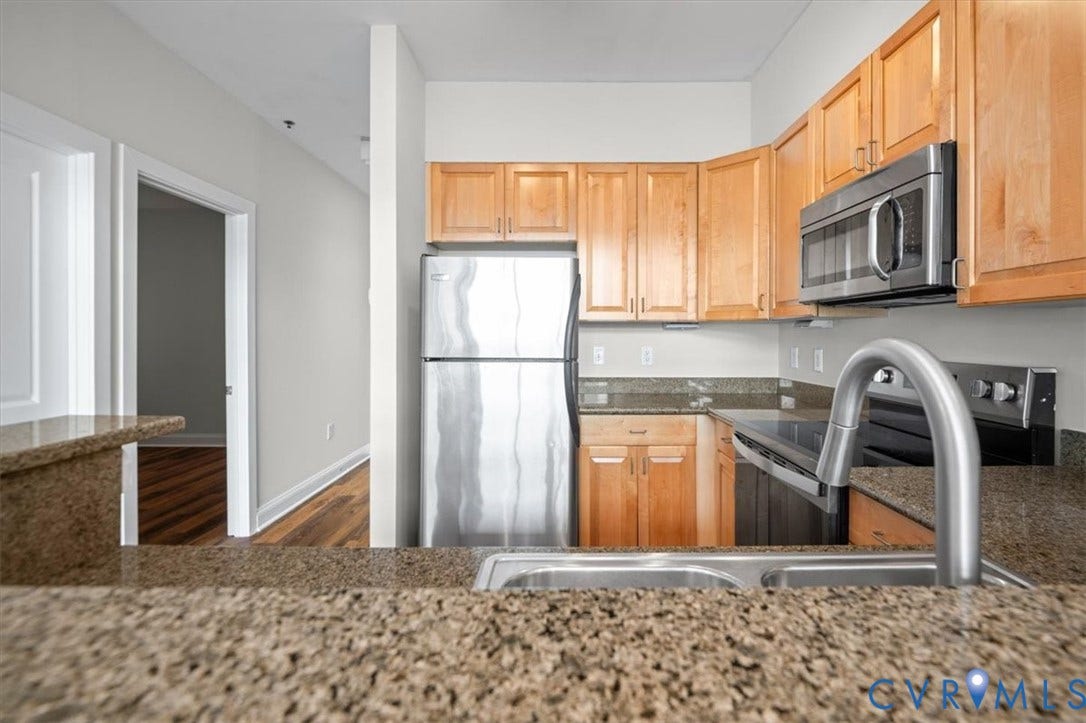 1333 Broad Street, #510, Ironhouse Place Condominiums, Richmond, VA 23220 Kitchen featuring warm wood cabinetry, stainless steel appliances, and stone countertops