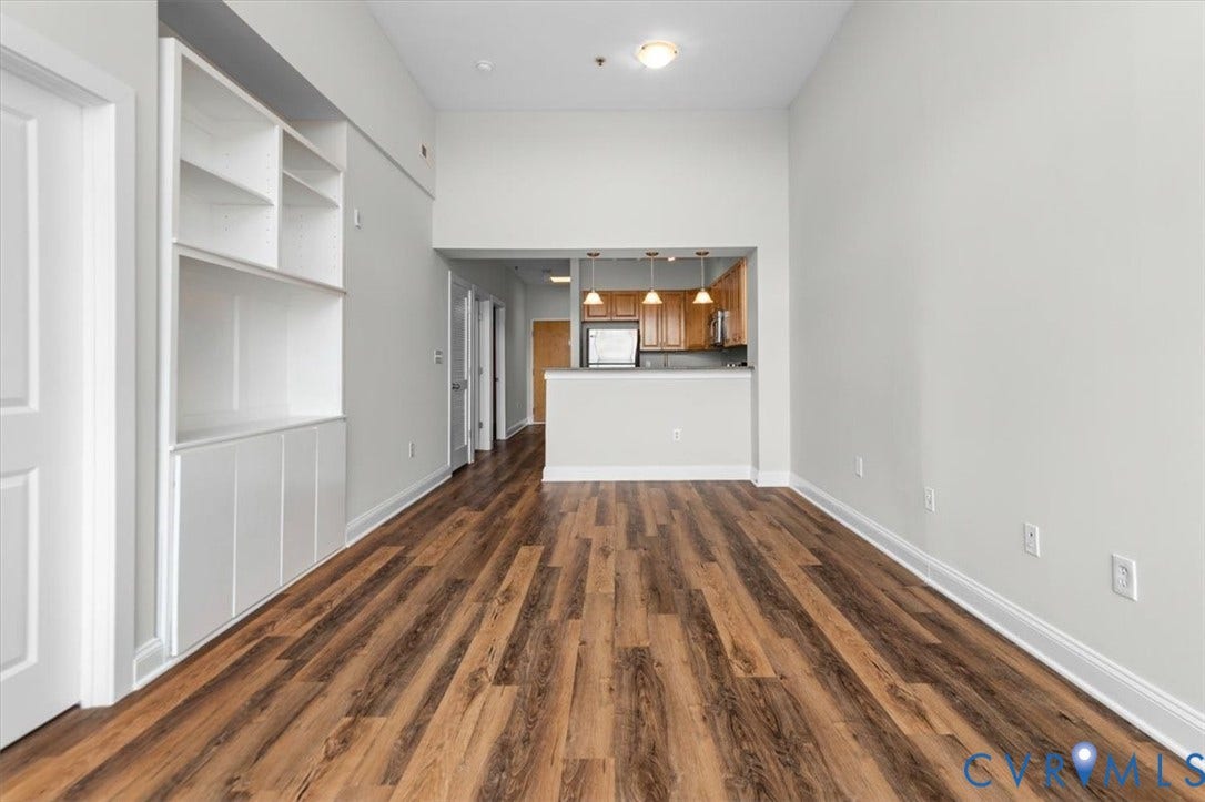 1333 Broad Street, #510, Ironhouse Place Condominiums, Richmond, VA 23220 Spacious living area featuring wood-finish flooring, high ceilings, and a built-in shelving unit with lower cabinetry