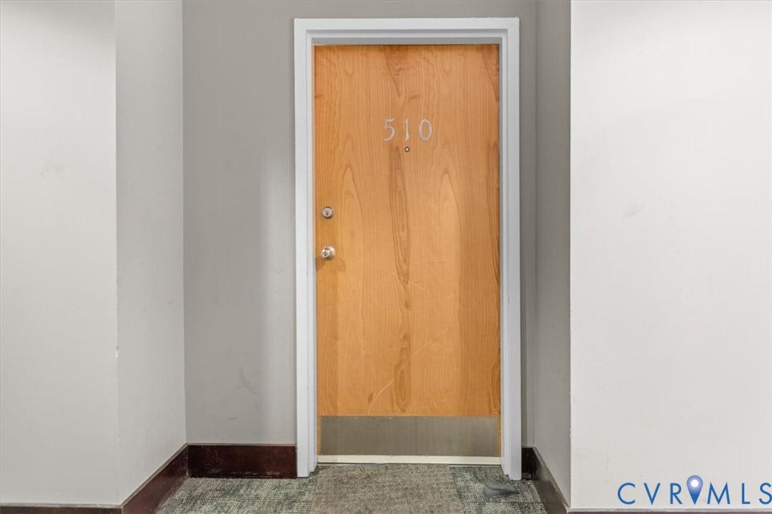1333 Broad Street, #510, Ironhouse Place Condominiums, Richmond, VA 23220 Natural wood-finish entry door with polished hardware, white trim, and a metal kickplate