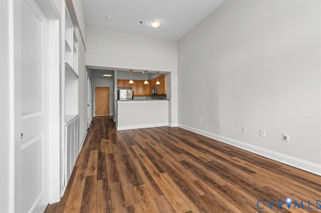 1333 Broad Street, #510, Ironhouse Place Condominiums, Richmond, VA 23220 Open-concept living space featuring wood-finish flooring, built-in shelving, vaulted ceilings, and a kitchen area with pendant lighting and stainless steel appliances