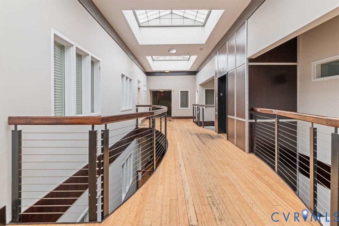 1333 Broad Street, #510, Ironhouse Place Condominiums, Richmond, VA 23220 Curved hallway featuring wood-finish flooring, multiple skylights, and contemporary cable railing