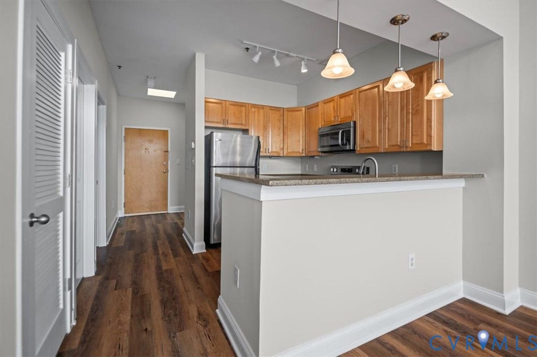 1333 Broad Street, #510, Ironhouse Place Condominiums, Richmond, VA 23220 Kitchen featuring wood cabinetry, stainless steel appliances, and a breakfast bar with pendant lighting