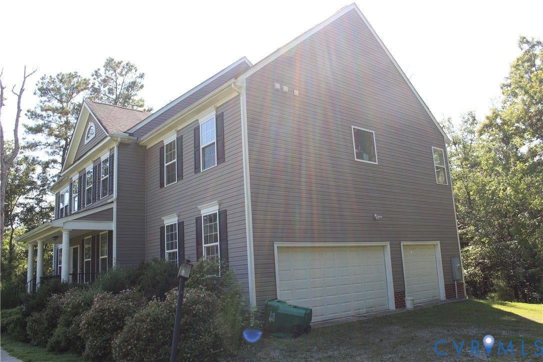 Two-story residence featuring grey horizontal siding, white trim, and dark window shutters