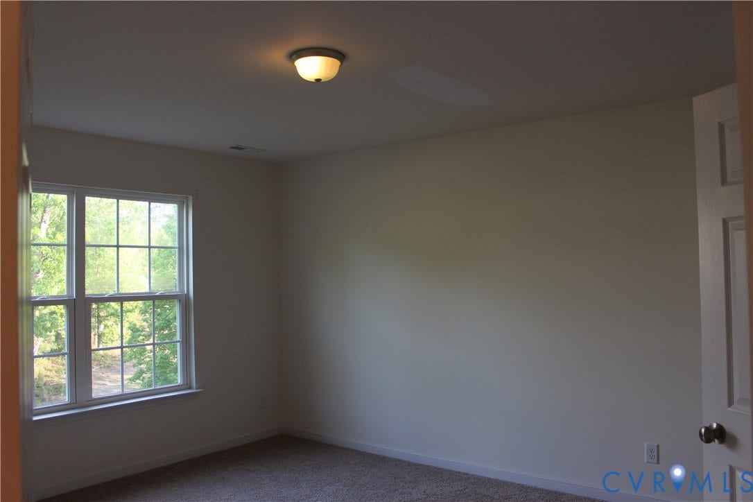 Room featuring neutral wall tones, carpet flooring, a multi-pane window, and a flush mount ceiling light fixture