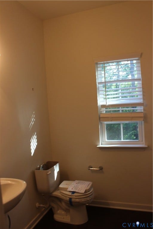 Compact bathroom featuring dark flooring, a white toilet, and a white sink