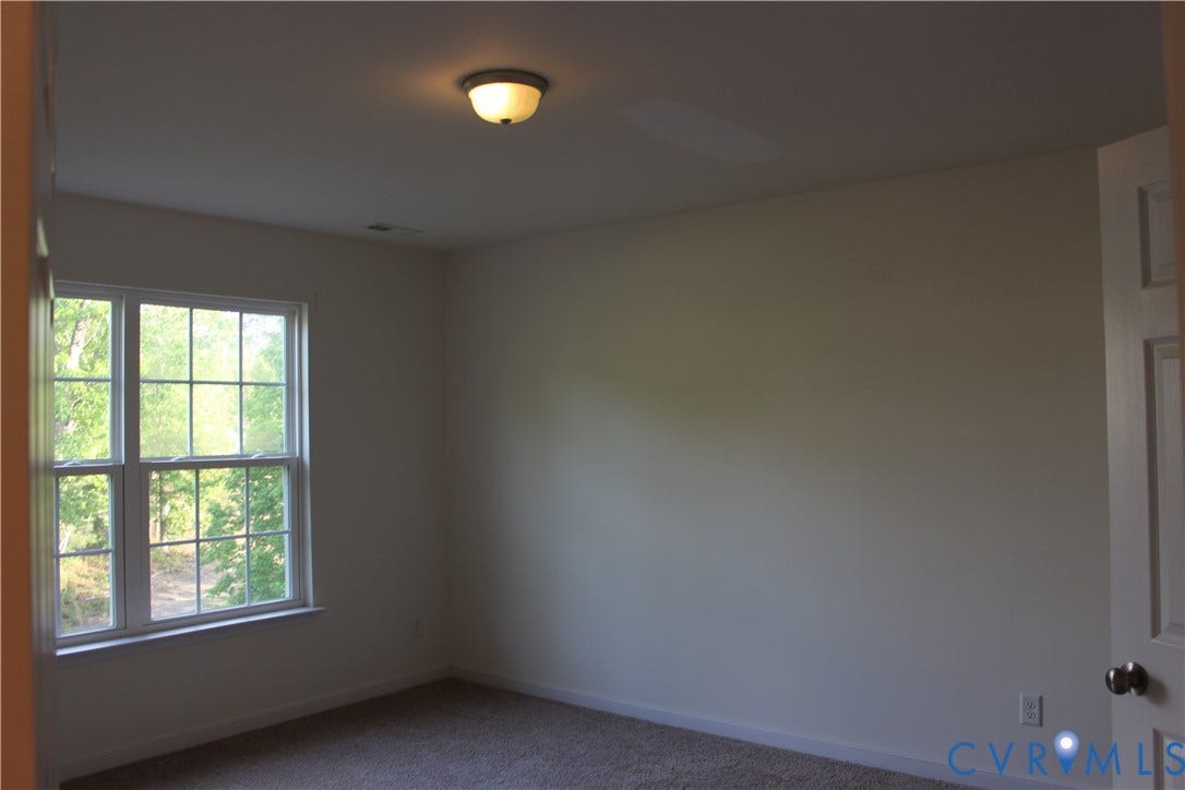 Room featuring neutral-toned walls, carpeted flooring, and a multi-paned window