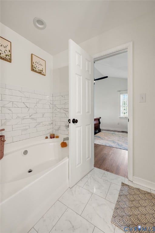 5612 Jessup Station Place, Chesterfield, VA 23234 White subway tile bath surround, white soaking tub, marble-look tile flooring, and a recessed ceiling light fixture